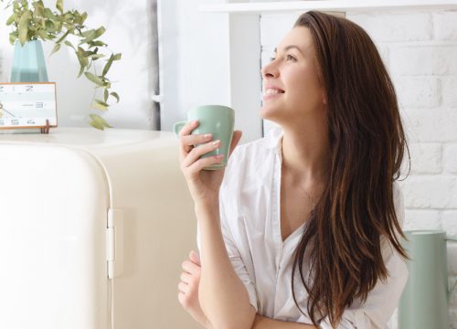 Happy woman holding a coffee cup in her living room