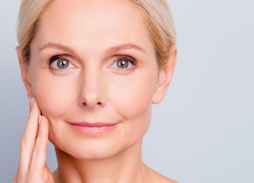 Older woman with facial volume loss touching her face