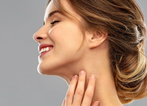 Woman touching her submental area after KYBELLA® chin treatments
