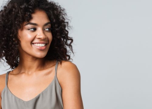 Smiling woman wearing a gray dress with slight keloids on her skin